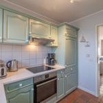 Küche mit hellblauen Schränken, Edelstahlgeräten und Blick in das Esszimmer.