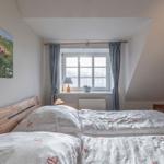 Schlafzimmer mit Doppelbett, Fenster und Wandbild.