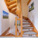 Holz-Treppe mit grauen Stufenbezug, Wandbilder und weißer Wand.