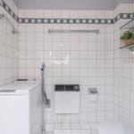 Badezimmer mit Waschmaschine, Toilette und Dusche
