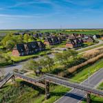 Dorf mit roten Häusern und grünen Wiesen unter blauem Himmel.