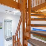 Holzspindeltreppe mit Teppichstufen führt zur oberen Etage. Neben dem Flur ist eine Dusche sichtbar.