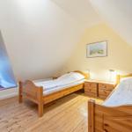 Zwei Einzelbetten, Holzboden und ein Fenster im Dachgeschosszimmer.