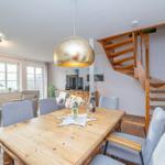 Essbereich mit Holztisch, grauen Stühlen und goldenem Hängelampen. Holz-Treppe führt nach oben.