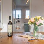 Ein Tisch mit Weinflasche, zwei Gläsern und einer Blumenvase.