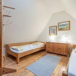 Zimmer mit zwei Betten, Holzmöbel und Schrägdach. Holzfußboden und Teppich.