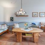 Wohnzimmer mit Holzmöbeln, Tisch und Sofa. Wanddekoration und Deckenleuchte.