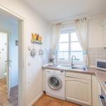 Küche mit Waschmaschine, Spüle und Fenster. Badezimmer ist angrenzend.