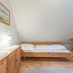 Schlafzimmer mit Holzbett, Schrank und Stuhl unter schräger Decke.