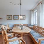 Esszimmer mit Holztisch, Stühlen und Fensterbank. An der Wand hängen zwei Bilder.
