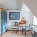 Schlafzimmer mit Kleiderschrank, Schreibtisch und Stühlen unter Dachschrägen.