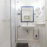 Badezimmer mit Dusche, Waschbecken und Spiegel mit blauem Rahmen.