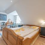 Schlafzimmer mit Holzbett, Schminktisch und Kleiderschrank unter schrägem Dach.