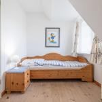Ein Schlafzimmer mit Holzbett, Nachttisch und Fenster unter Dachschrägen.
