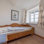 Ein Schlafzimmer mit Holzbett, Fenster und Wandbild.