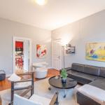 Wohnzimmer mit Ledersofa, Runden Tisch und Kunst an den Wänden.