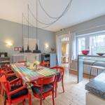 Esszimmer mit farbigem Tisch, roten Stühlen und Kücheninsel mit Arbeitsplatte.