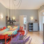 Esszimmer mit Tisch, Stühlen und Wandbild. Holzboden und Licht.