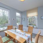 Esszimmer mit Holztisch, Stühlen und Fenstern zur Terrasse