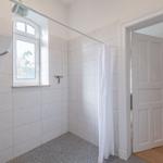 Badezimmer mit Dusche, Fenster und Blick in Schlafzimmer.