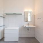 Badezimmer mit Waschbecken, Spiegel und Heizkörper an der Wand.