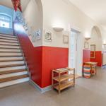 Hausflur mit Treppe, roten Wänden und Holzmöbeln.