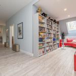 Großes Wohnzimmer mit Bücherregalen, rotem Sofa und Holzboden.