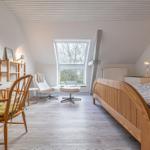 Schlafzimmer mit Holzbett, Schreibtisch und Sessel unter Dachschrägen.