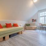 Ein Zimmer mit Schlafcouch, kleiner Sitzbank, Schreibtisch und großem Fenster.