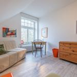 Ein Raum mit Sofa, Schreibtisch, Kleiderschrank und Fenster mit Blick nach draußen.