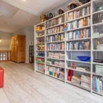 Große Bibliothek mit Bücherregalen, rotem Sitzkissen und Holzfußboden.