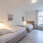 Zwei Betten, Fenster mit Blick, Wandbilder, Beleuchtung und Holzboden.