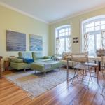 Wohn- und Essbereich mit grünem Sofa, Holzboden und großen Fenstern.