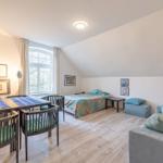 Zimmer mit Schlafplatz, Sitzgelegenheit und Esstisch unter Dachschrägen.