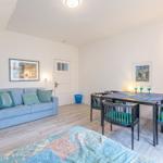 Wohn- und Essbereich mit Sofa, Tisch und Stühlen sowie Wandbildern.