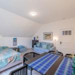 Schlafzimmer mit Sofa, Tisch und Bett unter Dachschrägen.