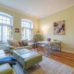 Wohn- und Essbereich mit grünem Sofa, Holzboden und zwei Bogenfenstern.