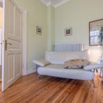 Ein Raum mit einem weißen Sofa, Holzboden und einer Tür zum Flur.