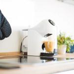 Eine Kaffeemaschine gießt Kaffee in ein Glas auf der Arbeitsfläche.