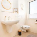Badezimmer mit Waschbecken, Toilette und Fenster. Dekoration mit Pflanzen und Spiegel.