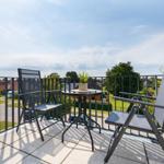 Terrasse mit zwei Stühlen und Tisch, Blick auf Wohngebiet und Bäume.