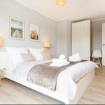 Ein Schlafzimmer mit Bett, Nachttisch, Lampen und Bildern an der Wand.