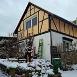 Fachwerkhäuser mit Schnee bedeckt, Garten mit Schnee und Gartenmöbeln.