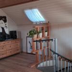 Dachgeschosswohnung mit Holzboden, Treppe, Pflanzenregal und Küchenzeile.