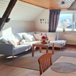 Wohn- und Essbereich mit Sofa, Tisch und Blick aus dem Fenster.