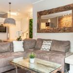 Wohnzimmer mit Sofa, Couchtisch und Kamin. Großer Spiegel an der Wand.