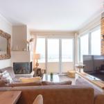 Wohnzimmer mit Sofa, Kamin und TV an Holzwand