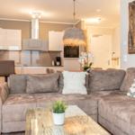 Wohnbereich mit Sofa, Couchtisch und Küche im Hintergrund.