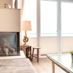 Wohnzimmer mit Kamin, Glas-Tisch und Fenster zur Aussicht.