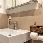 Bad mit Waschbecken, Spiegel und Toilettenpapierhalter.